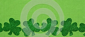 Green glitter shamrock border on green linen background
