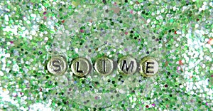 Green glitter slime and golden letters Slime, partial blur.