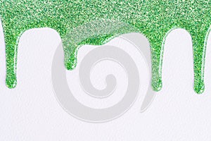 Green glitter sparkle confetti background liquid drops of paint color flow down on white canvas. Macro photo.