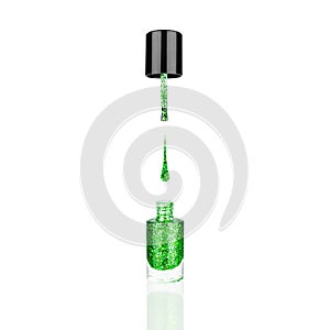 Green glittering nail polish glass bottle, brush, flowing drop white background isolated closeup, open green sequin varnish