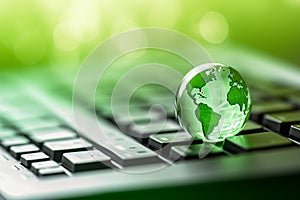 Green globe on a laptop keyboard with green bokeh background