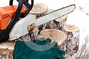 Green gloves for work with a chainsaw protecting from vibration and a chainsaw on a stump