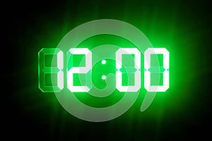 Green glowing digital clocks in the dark show 12:00 time