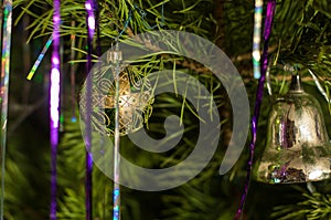 Green-gold ball, silver bell and tinsel hang