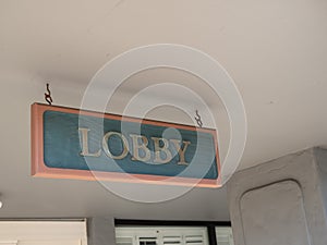 Green and gold lobby sign hanging outside at entrance of hotel