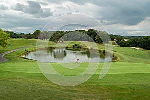 Between green golf courses and a lake under a very cloudy sky