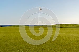 Green golf with flag and hole facing Atlantico photo