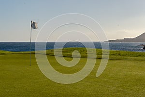 Green golf with flag and hole facing Atlantico ocean in Santa Cr