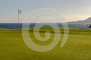 Green golf with flag and hole facing Atlantico ocean in Santa Cr