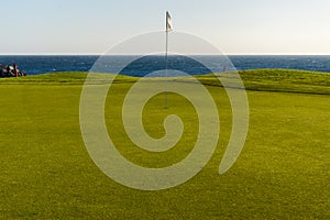 Green golf with flag and hole facing Atlantico ocean in Santa Cr