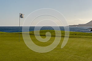 Green golf with flag and hole facing Atlantico ocean in Santa Cr photo