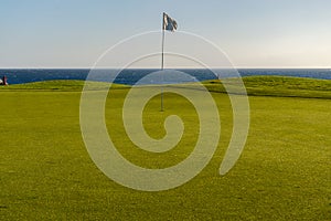 Green golf with flag and hole facing Atlantico ocean in Santa Cr photo