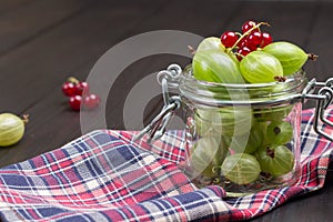 Green gooseberries in glass jar and on napkin