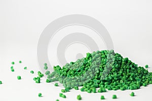 Green granules of polypropylene or polyamide on a white background. Plastics and polymers industry. Copy space.