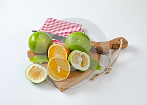 Green grapefruits and halved orange