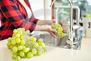 Green grapes on the first plan and a woman rinses  the green grapes photo