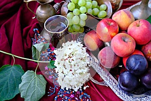 Green grapes, plums, peaches, nectarines, jugs, a glass of wine, white hydrangea, a Dutch still life on a silk tablecloth, with