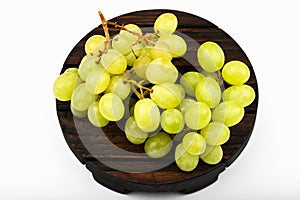 Green grapes on a round wooden plate. White background. view from above. A place to write. Juicy bunch of grapes on a wooden
