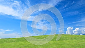 Green grass field on small hills and blue sky with clouds for background