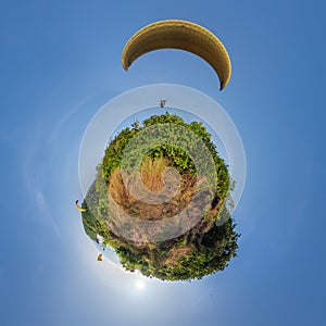 green grass little planet in blue sky with yellow paragliding parachute