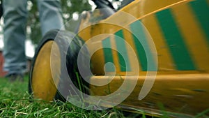 Green grass and man with lawnmower. low angle view, slow motion shot