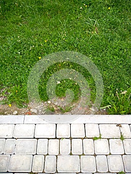 Green grass and white, grey pavements. Handmade and nature photo