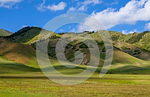 Green grassland, mountains, blue sky and white clouds