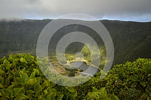 A green grassy bottom of an extinct crater with a small lake on the island