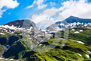 Green grassy hills, snow and peaked mountains