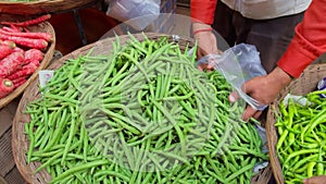 A green grocer man filling green beans in plastic bag at a market stall asian man in the local vegetable market buying veges India