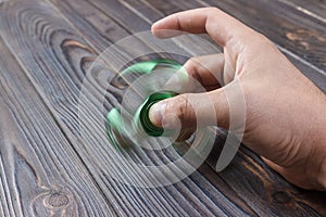 green hand spinner, or fidgeting spinner, rotating on man's hand