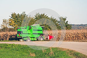 A green harvester harvests a corn field