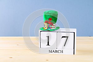 A green hat on a wooden table. St.Patrick's Day. A wooden calendar showing March 17.