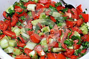 Green healthy organic freshly cut salad of fresh vegetables pieces and slices of tomatoes, cucumber, arugula leaves and onion with