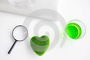 Green heart concept. Health Care researchs equipments. Green heart with a chemical organic test rube. Science glasses on laptop