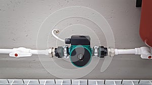 Green heating circulation pump mounted on a pipe. Independent heating system in boiler room at home