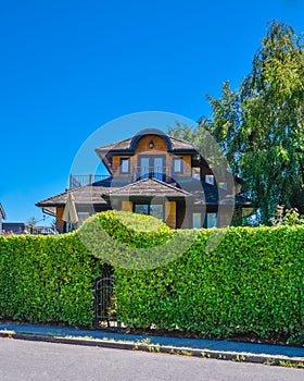 Green hedge with arch over entrance gate in front of residential house.