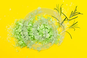 Green herbal bath salt with rosemary on a yellow background