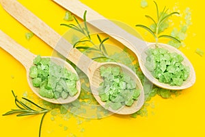 Green herbal bath salt with rosemary on a yellow background