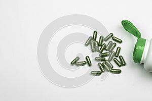 Green Herbal capsules pills from herbs on white background, pills top view