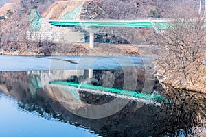 Green highway bridge over partially frozen river