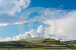 Green hill , blue sky with white fluffy clouds