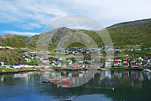 Green hill with fishing town on the side of fjord