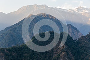 Green hill near Kangchenjunga mountain with clouds above and trees with sunlight that view in the evening in North Sikkim, India