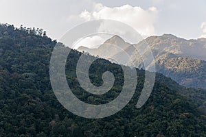 Green hill near Kangchenjunga mountain with clouds above and trees that view on the road in the evening in North Sikkim, India