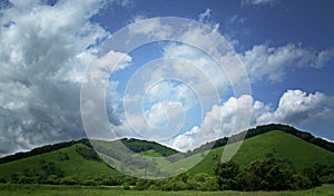 Green hills against blue sky with clouds