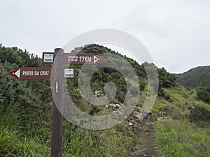 Green hills and meadow with footpath and tourist signpost pointing at Porto da Cruz in one direction and Percurso de photo