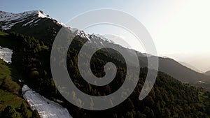 Green hills and Mountains covered in snow, aerial view. Beautiful untouched nature of Kyrgyzstan. Travel concept