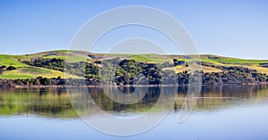 Green hills reflected on the calm waters of Tomales Bay, North San Francisco Bay Area, California