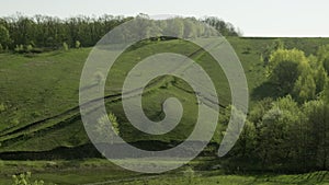 Green hillside with trees and road. A large valley and pastures on the slopes. Summer hill Panorama